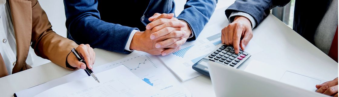 Liike-elämän ammattilaiset analysoimassa taloudellisia raportteja ja laskelmia pöydän ääressä.