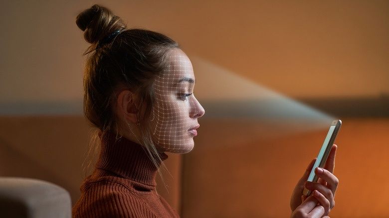 Nainen käyttää puhelinta, jonka kasvoilla näkyy kasvojentunnistuksen ruudukko